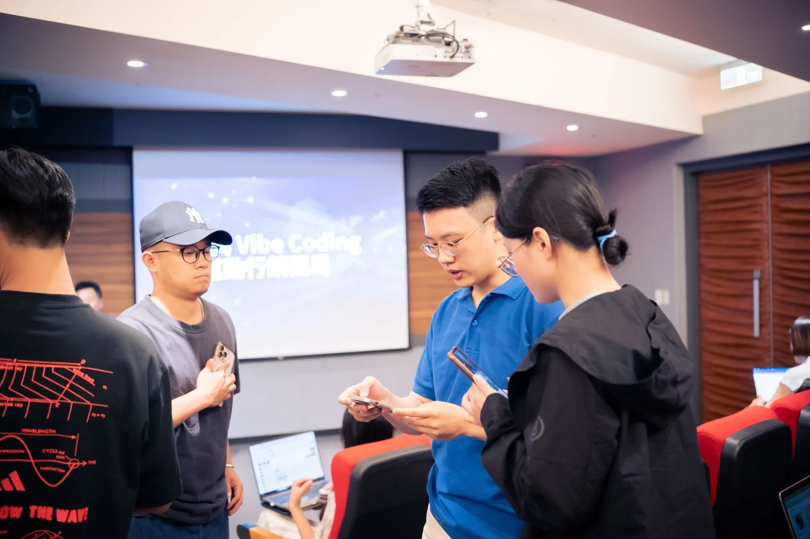 施文凱在教室裡和學員一起看手機上的操作畫面